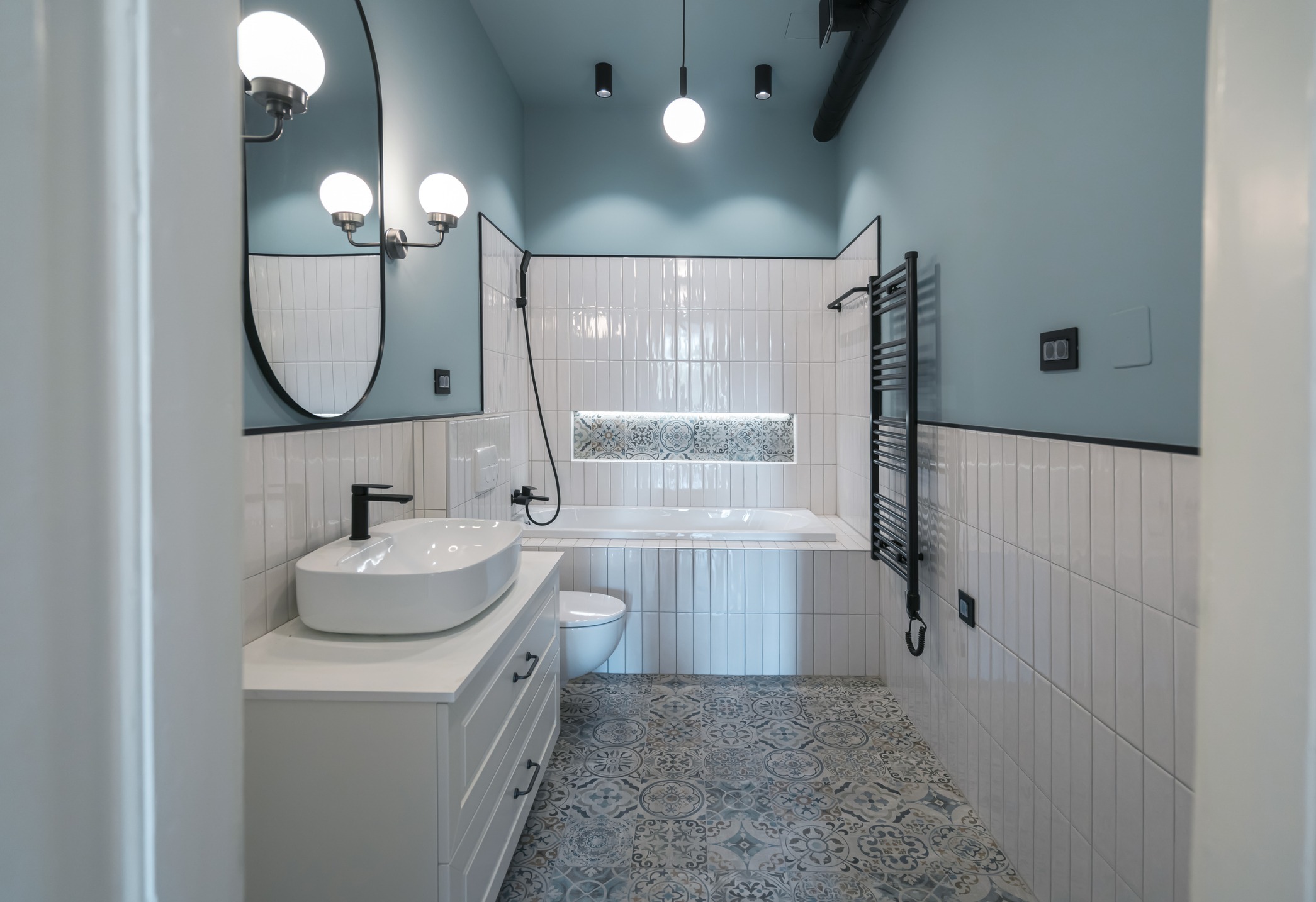 An upgraded luxury bathroom includes a lighted shelf beside the bathtub, as well as mosaic-style tiles for a statement floor.