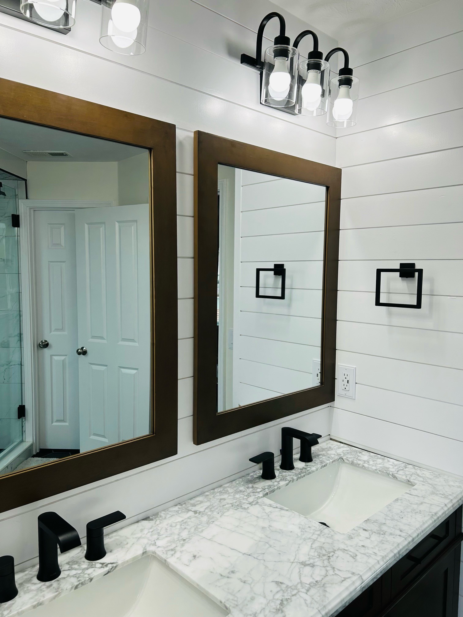 A modern bathroom combines style and function with black framed mirrors and a white marble sink.